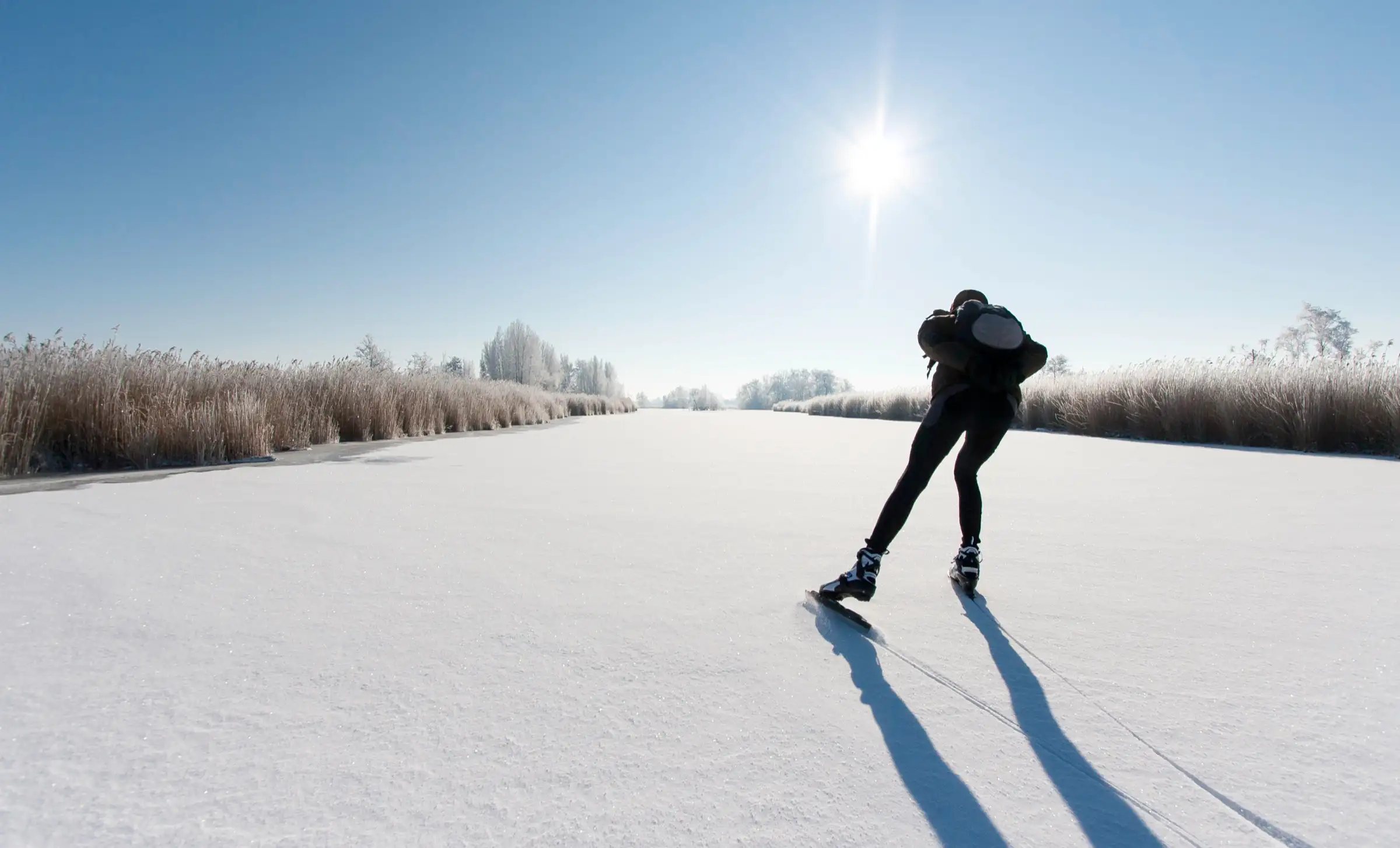 Schaatser op natuurijs in een besneeuwd landschap